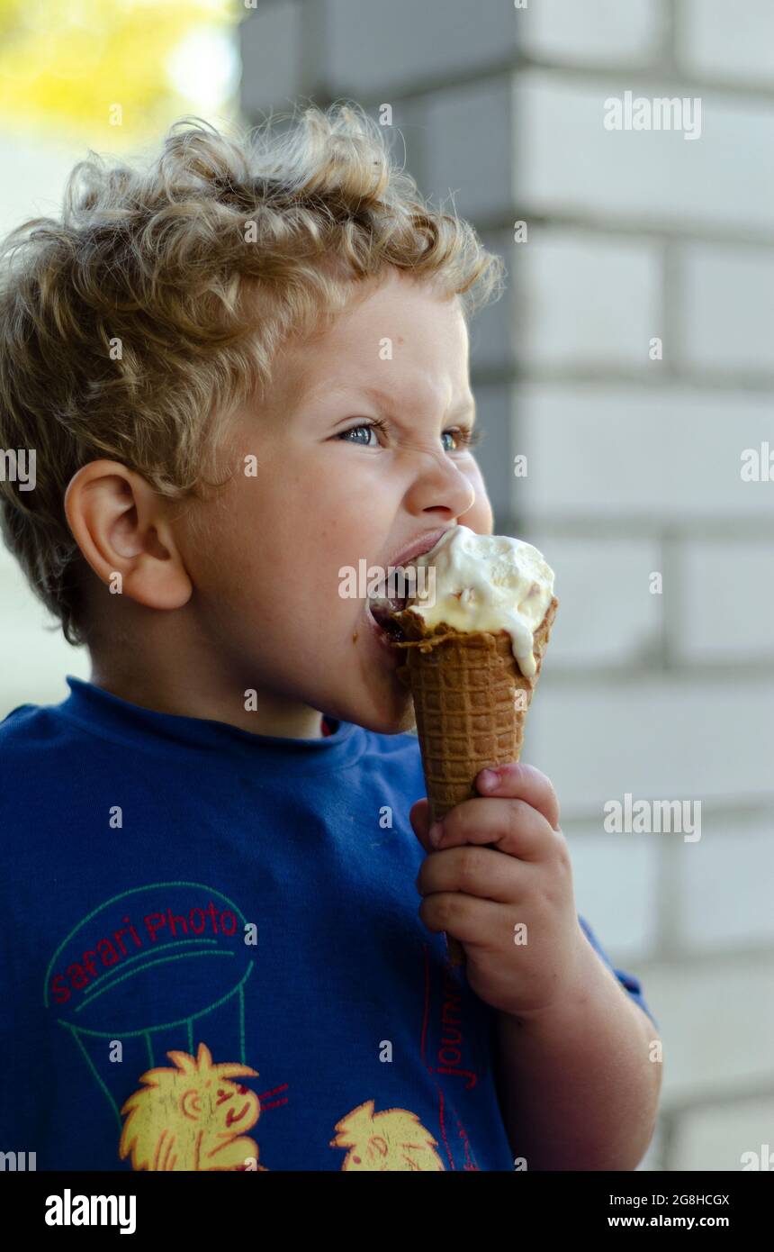 Junge 2 Jahre alt beißt Eis im Sommer Stockfoto