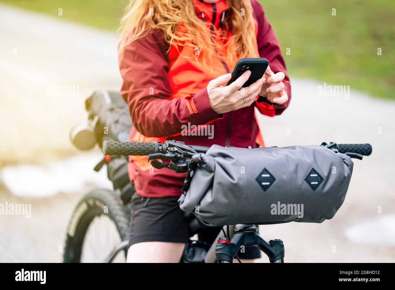 Frau genießt mit einem Mountainbike in der Natur, mit Smartphone Stockfoto
