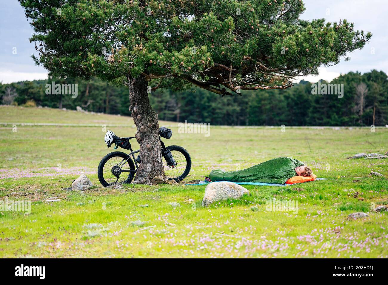 Frau, die neben dem Fahrrad im Schlafsack schläft Stockfoto