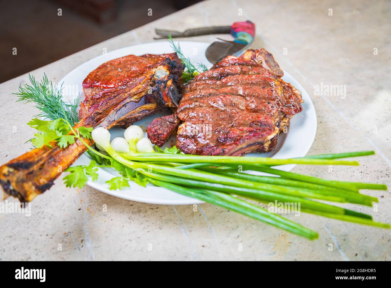 Gekochtes, gebratenes Fleisch mit Gewürzen auf einem weißen Teller. Im Ofen gebackenes Fleisch zum Abendessen mit einem Glas Rotwein. Nahaufnahme Stockfoto