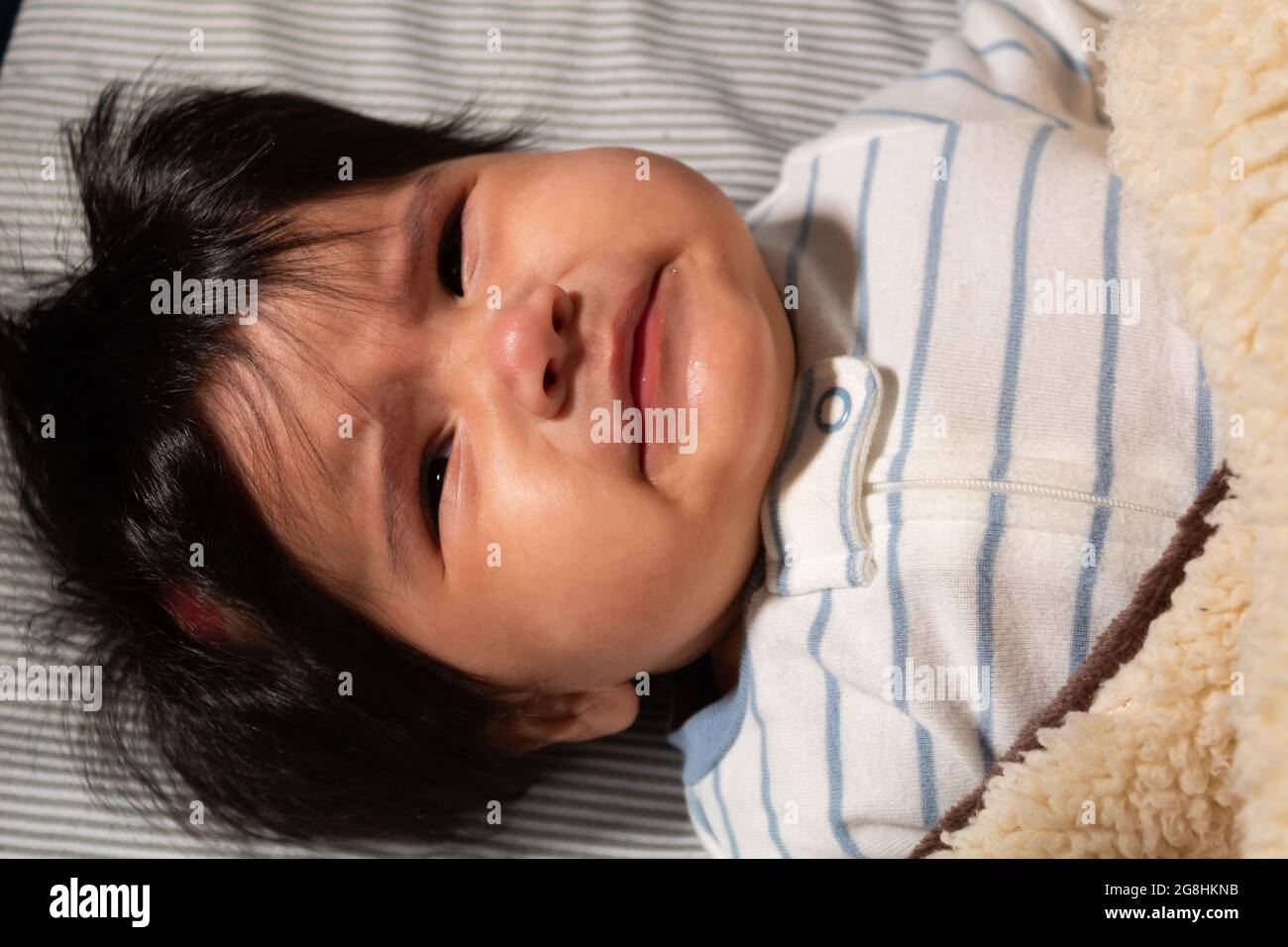 Porträt eines 5 Monate alten hispanischen Babys mit langen Haaren, die wütend und traurig aussehen Stockfoto