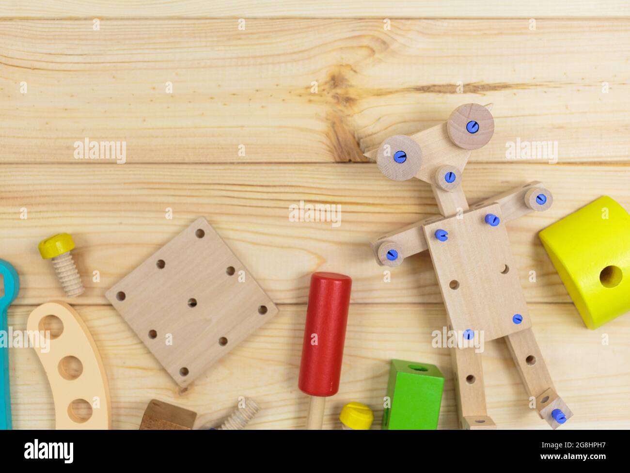 Ein farbenfroher Holzbausatz, ein Roboter für Kinder auf Holz. Set von Werkzeugen auf Holztisch. Spiele und Werkzeuge für Kinder in der Vorschule oder Kindertagesstätte. Natürlich, Stockfoto