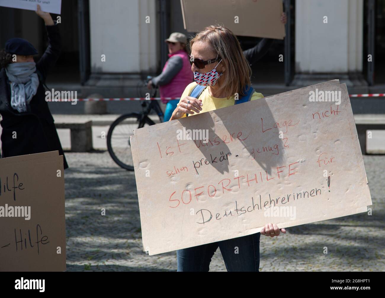 Demonstrantin hält Schild ' is our Lage not schon prekär genug? Soforthilfe für Deutschlehrerinnen! Bei einer Protestaktion für mehr Unterstützung von Freiberuflern, Solo-Selbstständigen und Selbstständigen in der Corona-Rise auf dem Geschwister-Scholl-Platz am 16. Mai 2020 in München. (Foto: Alexander Pohl/Sipa USA) Quelle: SIPA USA/Alamy Live News Stockfoto