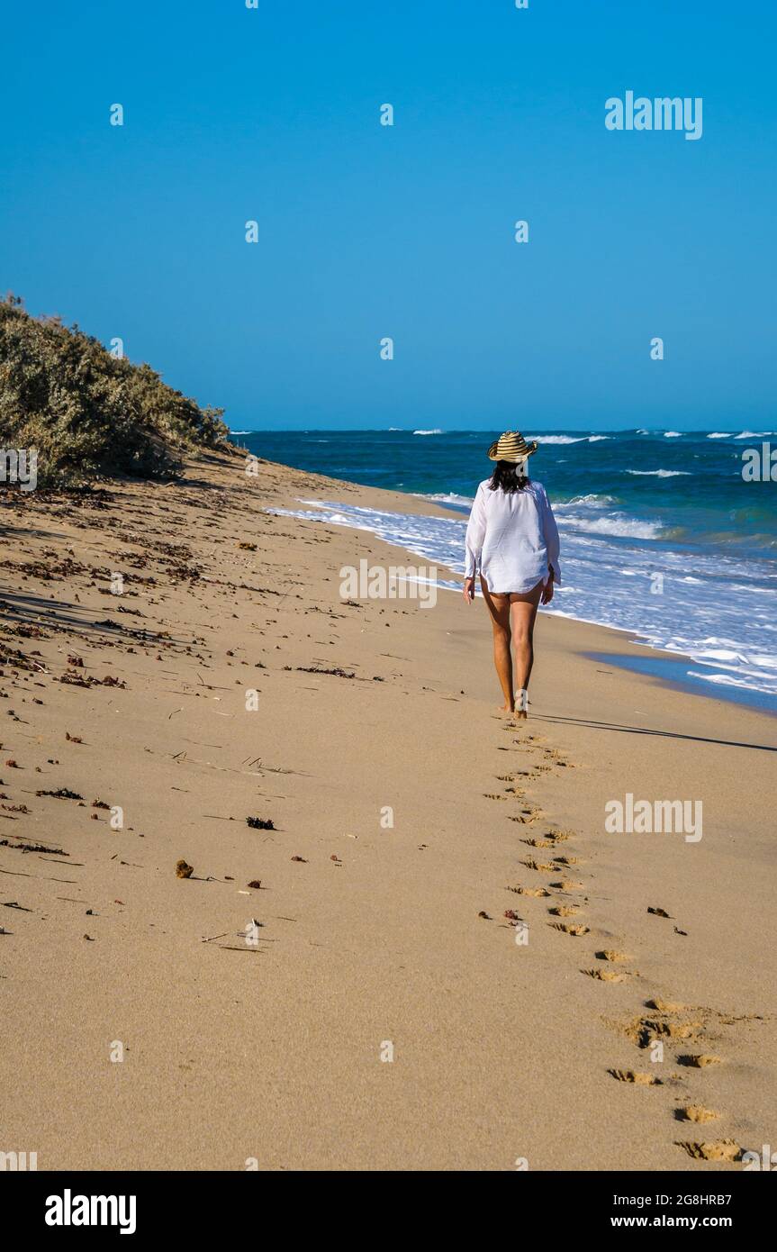 Eine alleinstehende weibliche Strandbegleiterin spaziert entlang eines Teils des Red Bluff Beach an der Quobba Station in der Gascoyne-Region von Western Australia. Stockfoto