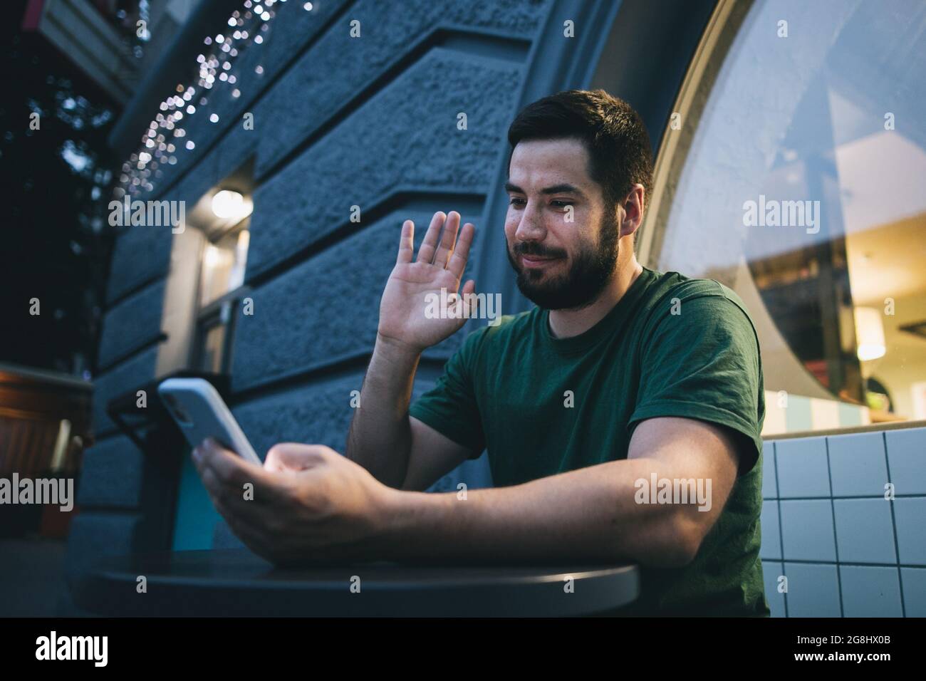 Ein junger Mann, der draußen den Videoanruf auf dem Mobiltelefon ansieht Stockfoto