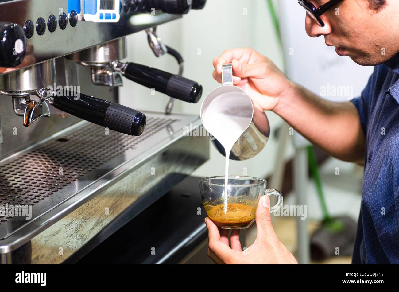 Hand des Barista, der Latte oder Cappuccino Kaffee macht, Milch gießt, um Latte Kunst zu machen Stockfoto