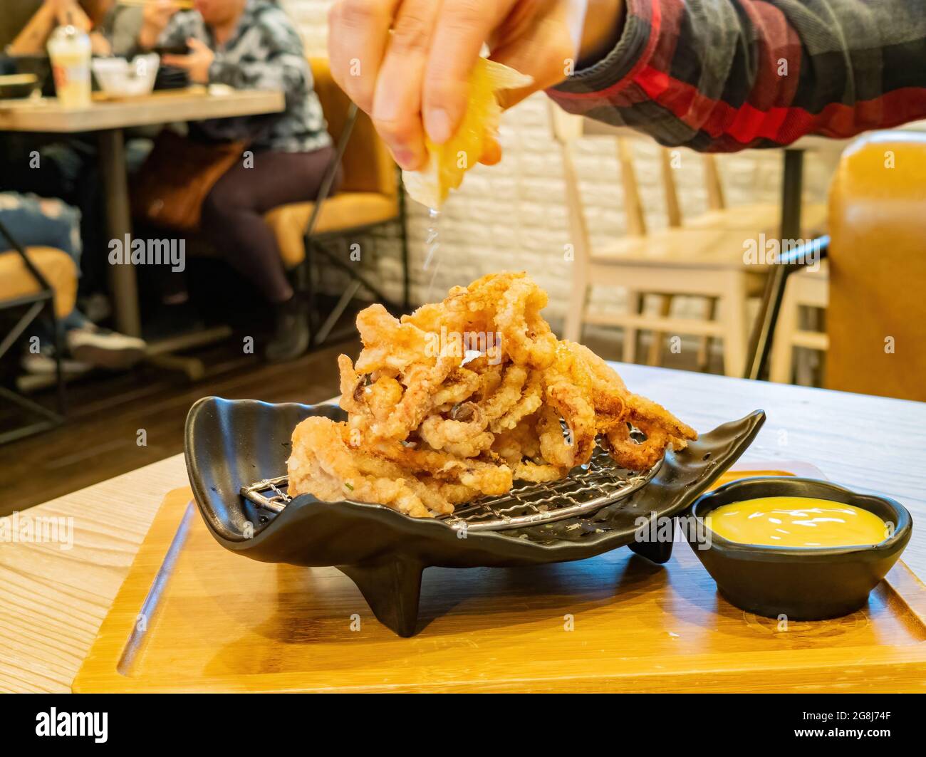 Nahaufnahme des Quetschens von Zitronensaft zu den Crispy Squid Tentakeln in Las Vegas, Nevada Stockfoto