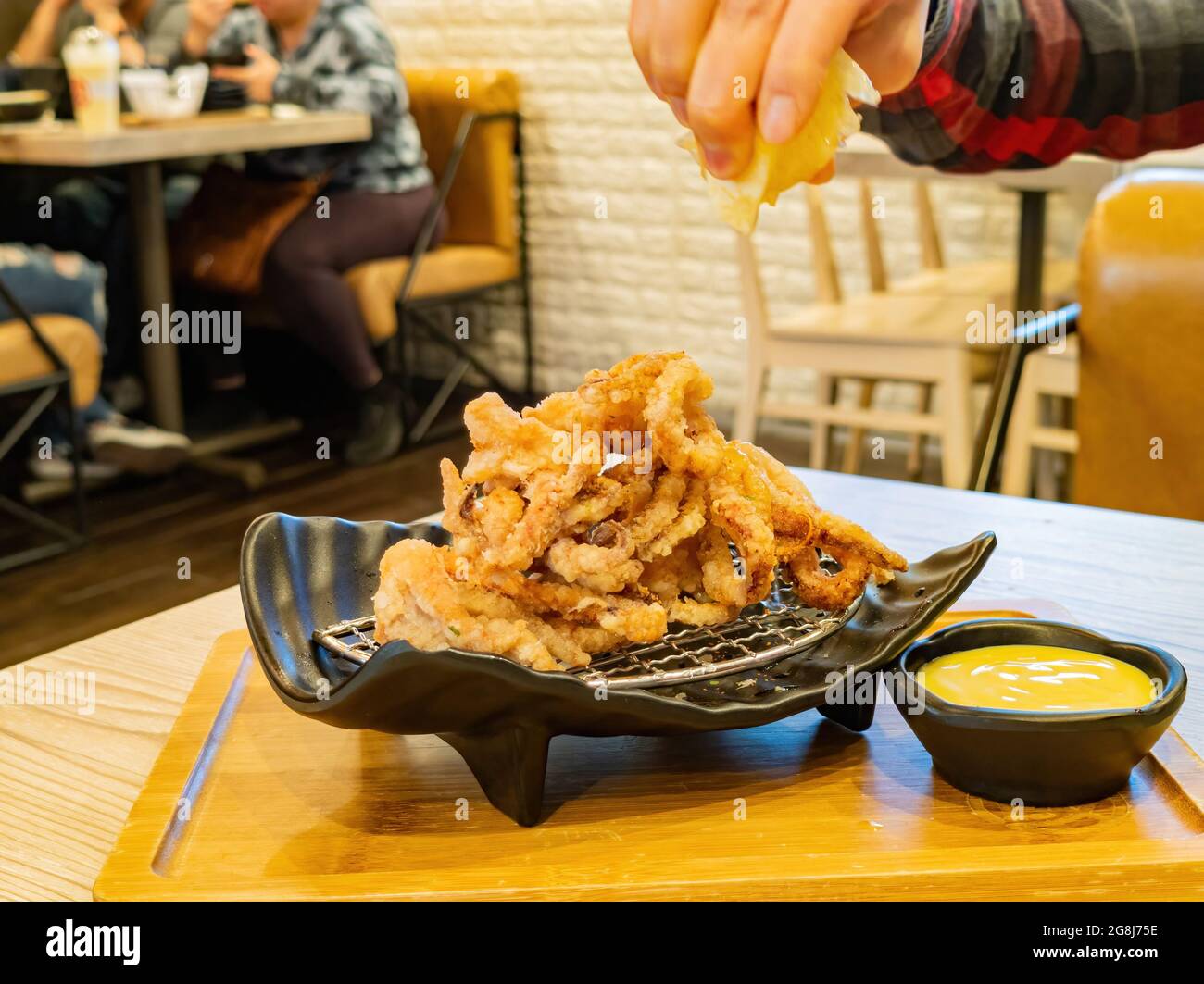 Nahaufnahme des Quetschens von Zitronensaft zu den Crispy Squid Tentakeln in Las Vegas, Nevada Stockfoto