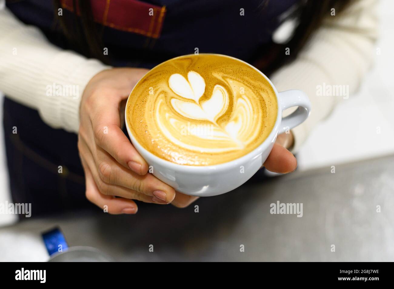 Hände eines jungen Barista, der Kaffee Latte Art macht Stockfoto