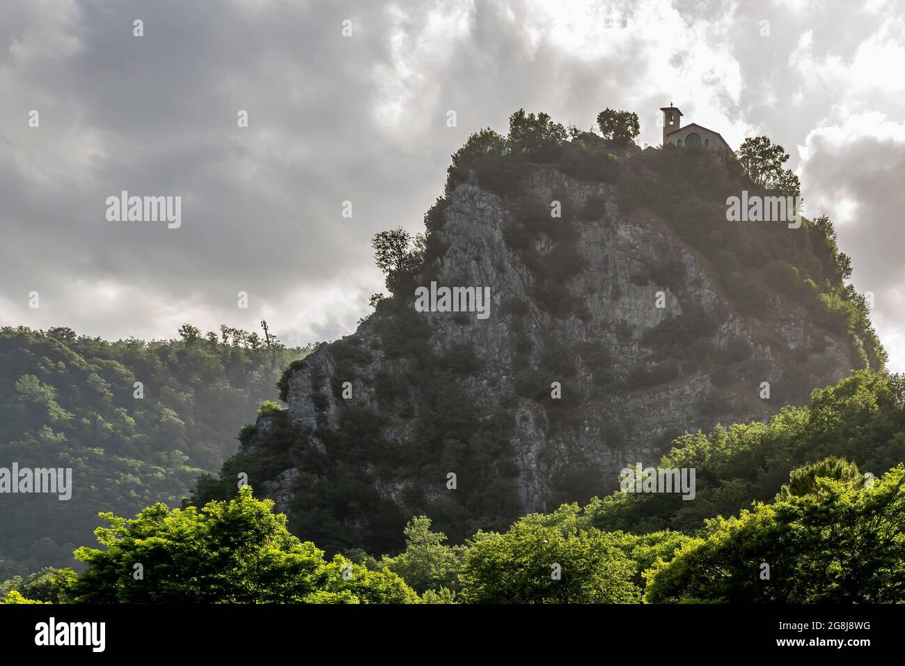 Blick von unten auf den Gebetskuppe von Roccaporena, Cascia, Italien oder Sacro Scoglio, unter einem dramatischen Himmel Stockfoto