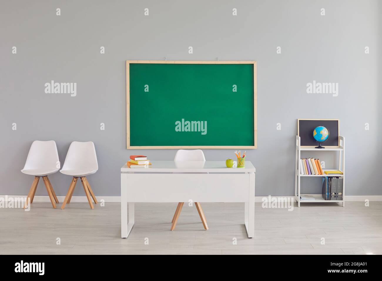 Moderne Einrichtung im Klassenzimmer mit Schreibtisch und Tafel für Lehrer, Platz für Design. Leerer Schulraum mit Möbeln Stockfoto