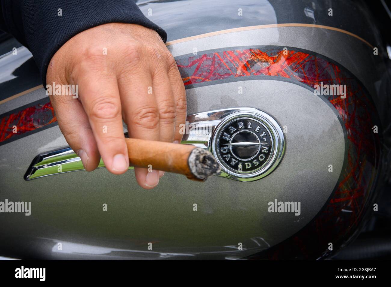 Dresden, Deutschland. Juli 2021. Ein Mitglied des Dresdner Harley Davidson Clubs, 'Dresden Chapter Germany Harley Owners Group', raucht auf seiner Harley während einer Presse- und Fotosession für die 'Harley Days Dresden 2021' auf dem Festivalgelände in der Flutrinne eine Zigarre. Die Neuauflage der Harley Days Dresden findet vom 23. Bis 25. Juli 2021 statt. Quelle: Robert Michael/dpa-Zentralbild/ZB/dpa/Alamy Live News Stockfoto