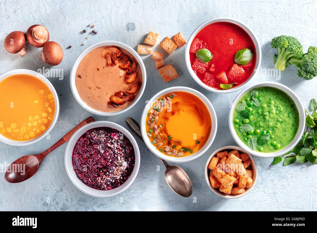 Bunte Gemüsesuppen, vegane Ernährung. Kürbis, Pilze, Rote Beete, Tomaten, Mais und grüne Erbsencremes, von oben mit Zutaten geschossen Stockfoto