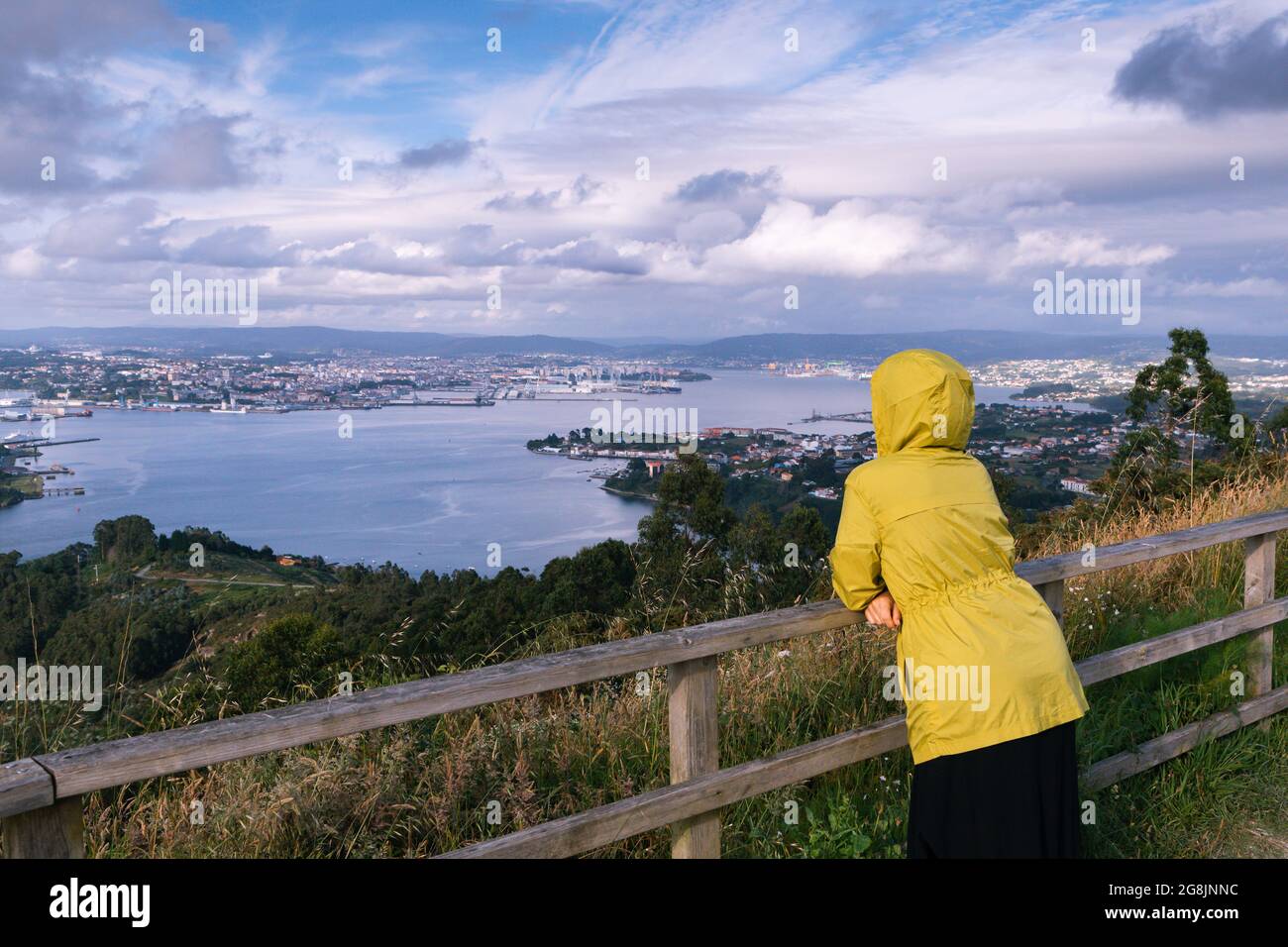 Frau mit Regenmantel, die die wunderschöne Landschaft einer spanischen Mündung im Norden Spaniens betrachtet Stockfoto