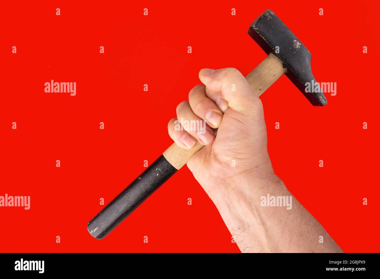 Ein Mann mit einem Hammer in der Hand und rotem Hintergrund Stockfoto