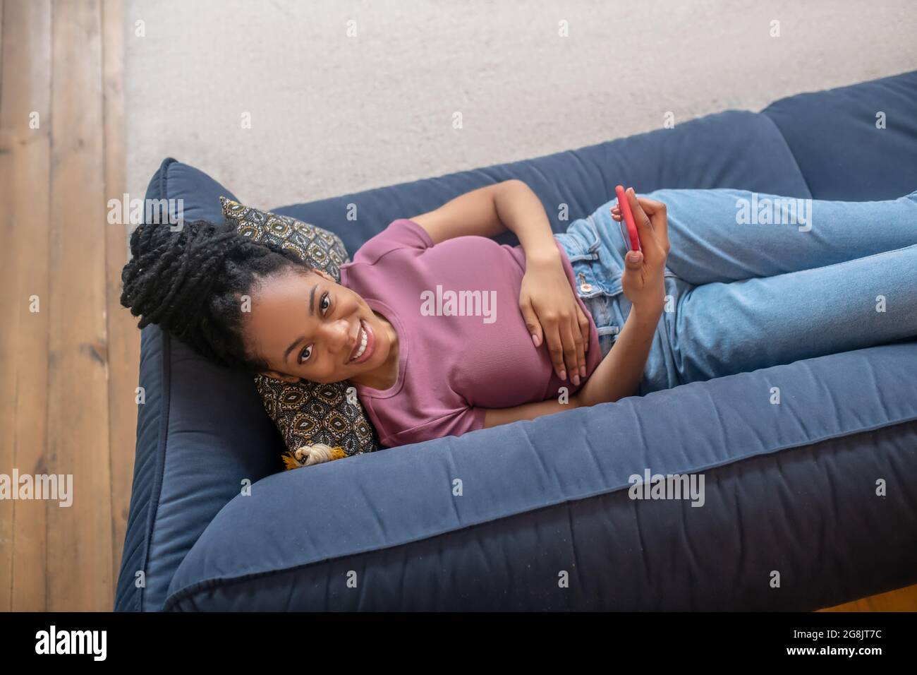 Schöne dunkelhäutige Frau, die Freizeit auf dem Sofa verbringt Stockfoto