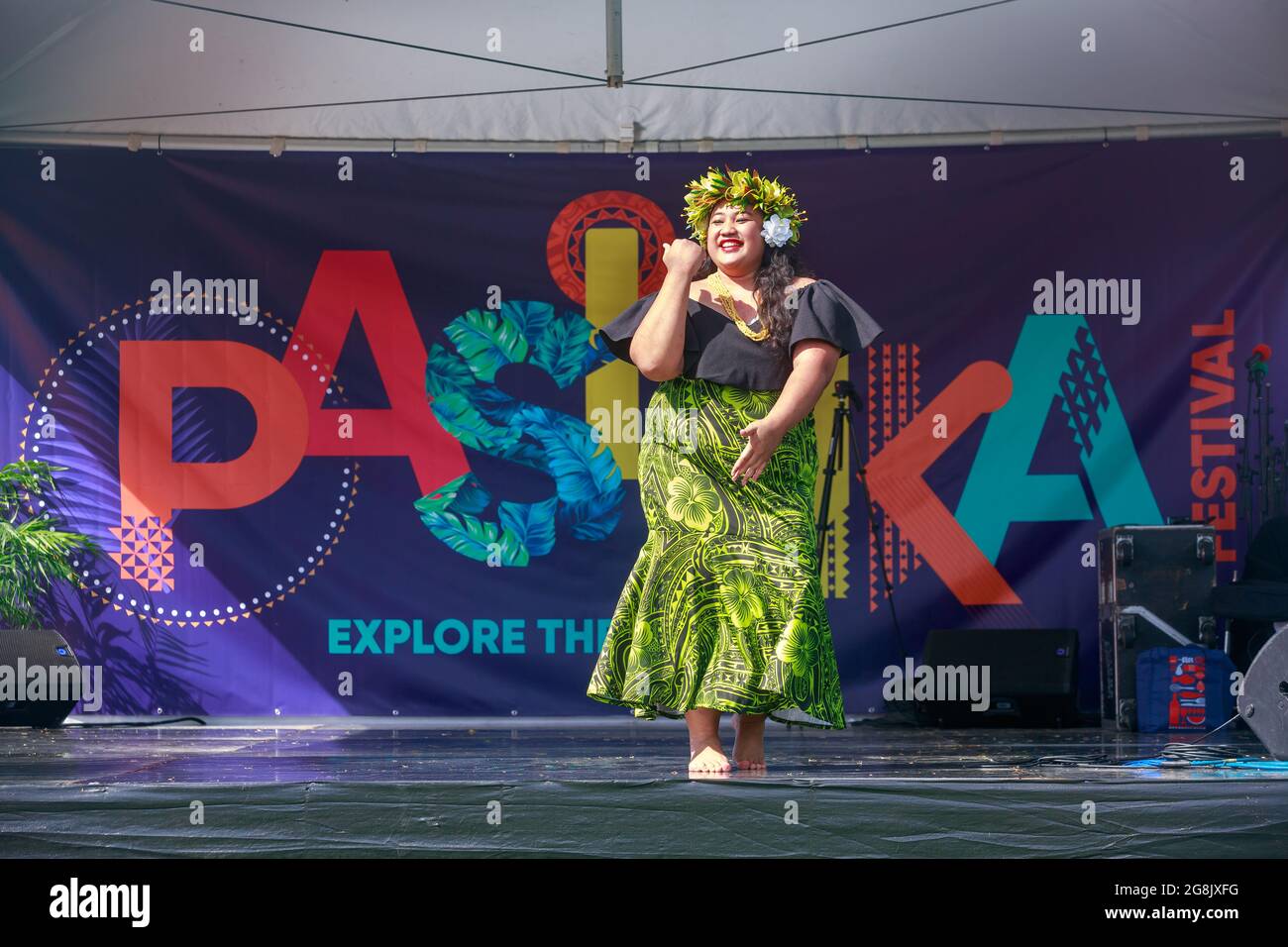Eine polynesische Frau, die vor dem Logo zum Pasifika Festival tanzt, einer Feier der Kultur der Pazifikinsel in Auckland, Neuseeland Stockfoto