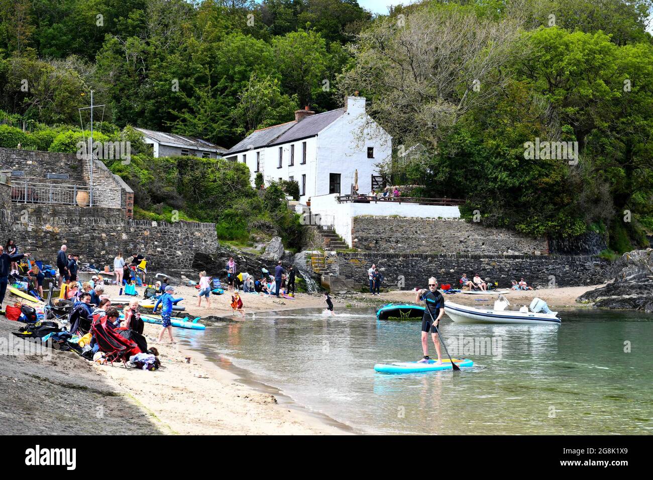 Die Menschen genießen ihre Zeit am Strand im malerischen Cwm-yr-Eglwys, Pembrokeshire, Südwales. Es wurde berichtet, dass das kleine Dorf am Meer mehr Ferienhäuser hat, als ständige Bewohner, wobei die Einheimischen vom Immobilienmarkt ausgepreist werden. Nur zwei der fünfzig Häuser im Dorf sind heute die Heimat von Einheimischen. Stockfoto