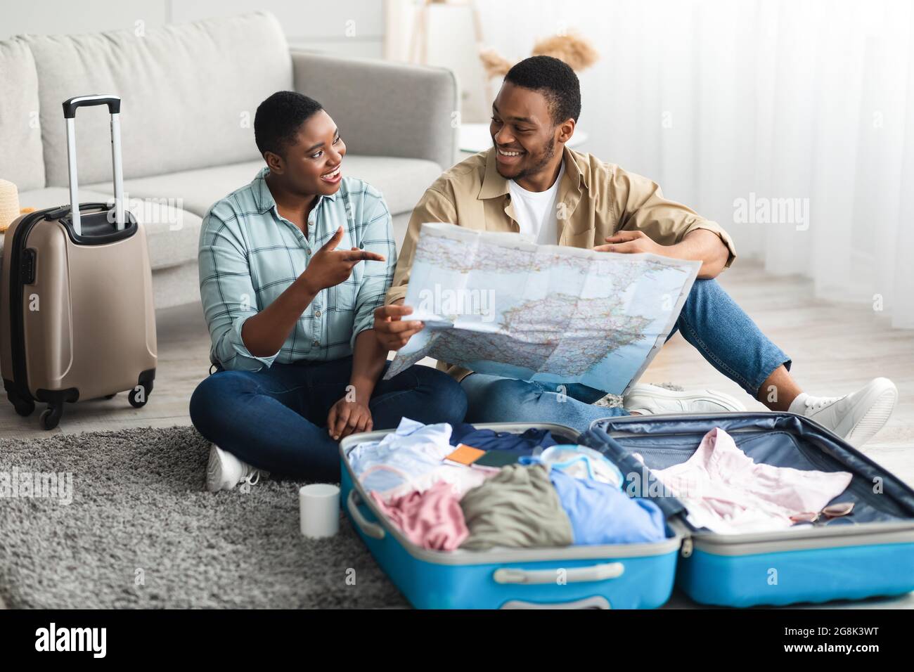 Afroamerikanische Familie, Die Sich Für Einen Urlaub Mit Karte Indoor Entscheidet Stockfoto