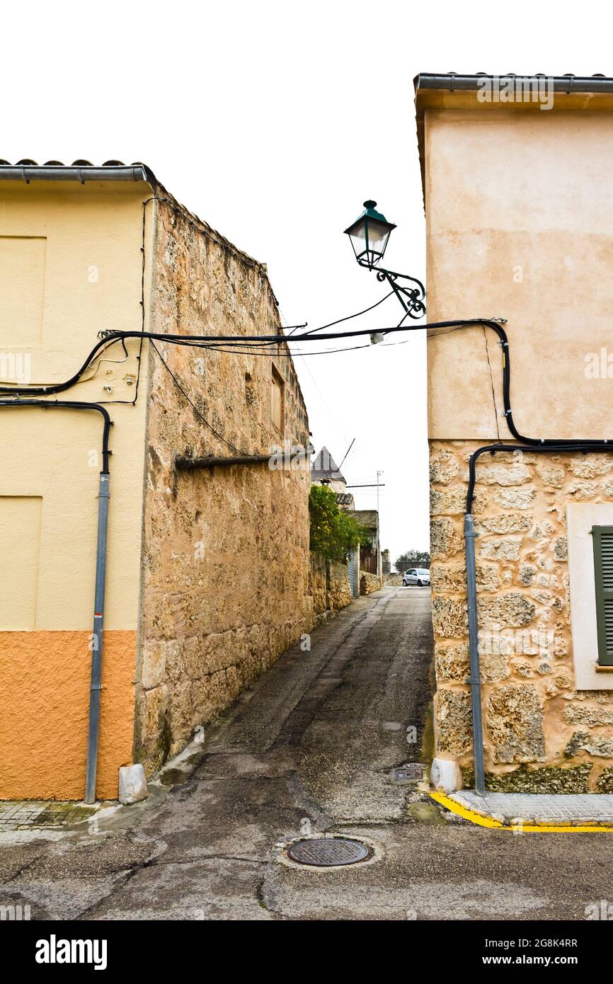 Extrem schmale Straße ohne Gehweg oder Bürgersteig und freiliegende elektrische Leitungen in Sineu, Mallorca oder Mallorca. Stockfoto