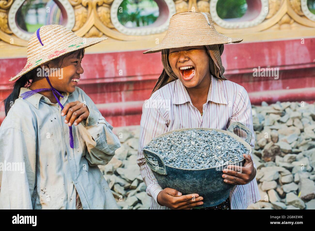 Junge, hübsche burmesische Kinderarbeiter, Straßenbauarbeiter, die einen Korb mit Steinen trugen und lachen, Monywa, Myanmar Stockfoto