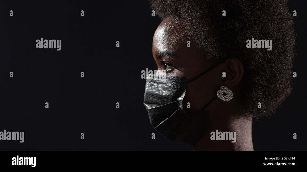 Profilansicht der afroamerikanischen Frau in schwarzer medizinischer Schutzmaske. Sicherheit bei Covid-19-Coronavirus-Pandemien Stockfoto