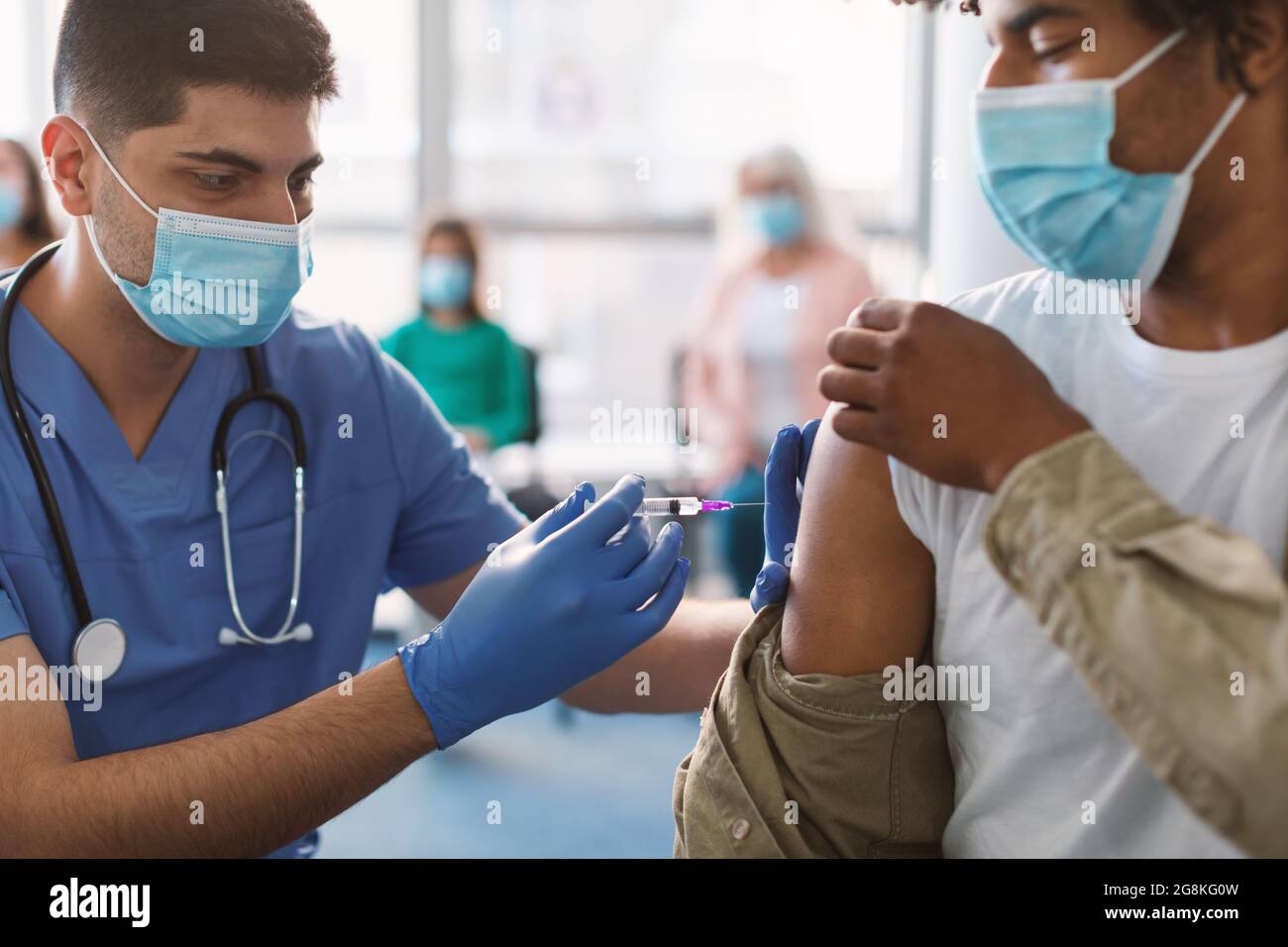 Schwarzer Mann Erhält Coronavirus-Impfstoff-Injektion Sitzt Mit Arzt In Der Halle Stockfoto