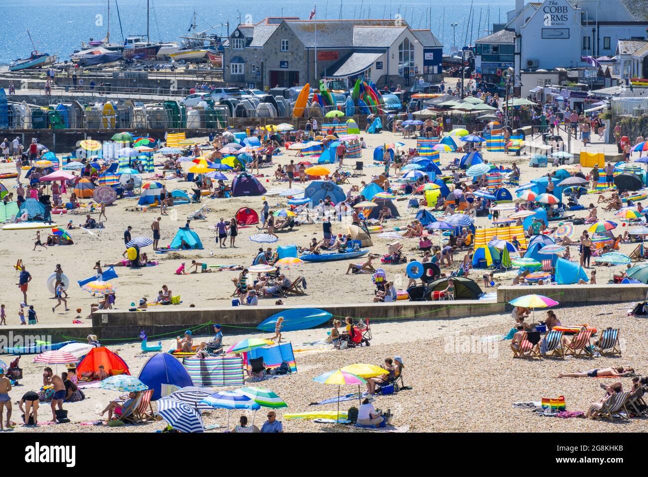 Lyme Regis, Dorset, Großbritannien. Juli 2021. UK Wetter: Massen von Strandbesuchern packten den malerischen Strand am Badeort Lyme Regis, als die Temperaturen heute Nachmittag wieder auf 30 Grad Celsius anstiegen. Urlauber und Strandbesucher schwelgen in Rekordtemperaturen, als das Met Office die bernsteinfarbene Warnung vor „extremer Hitze“ ausdehnte, während die Hitzewelle bis zum Ende der Woche andauert. Kredit: Celia McMahon/Alamy Live Nachrichten Stockfoto