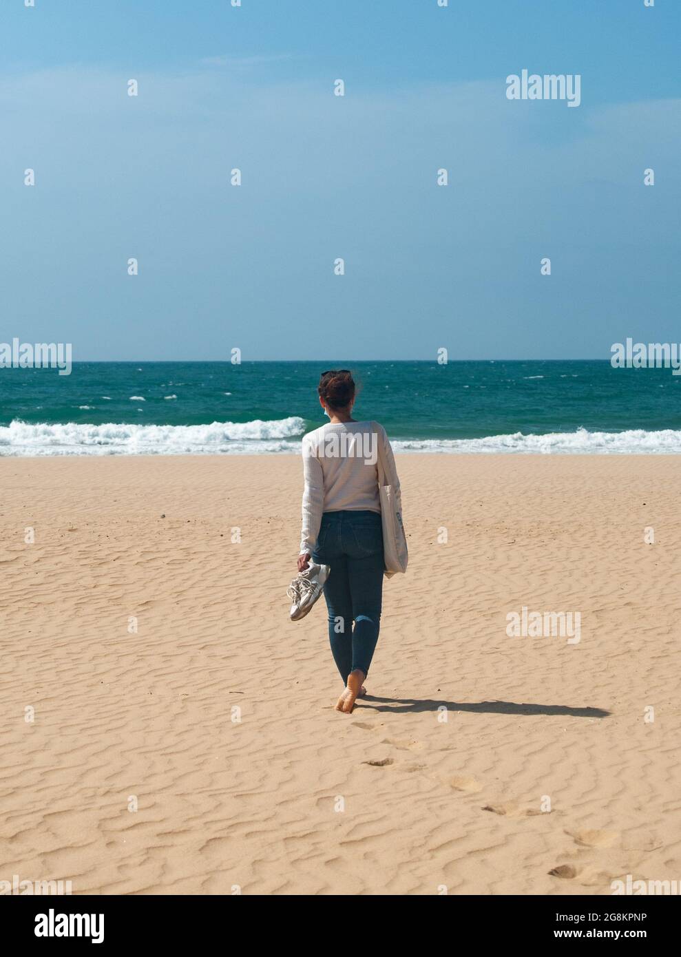 Ein Mädchen geht an einem portugiesischen Strand entlang, Algarve, Portugal - Platz für Text Stockfoto
