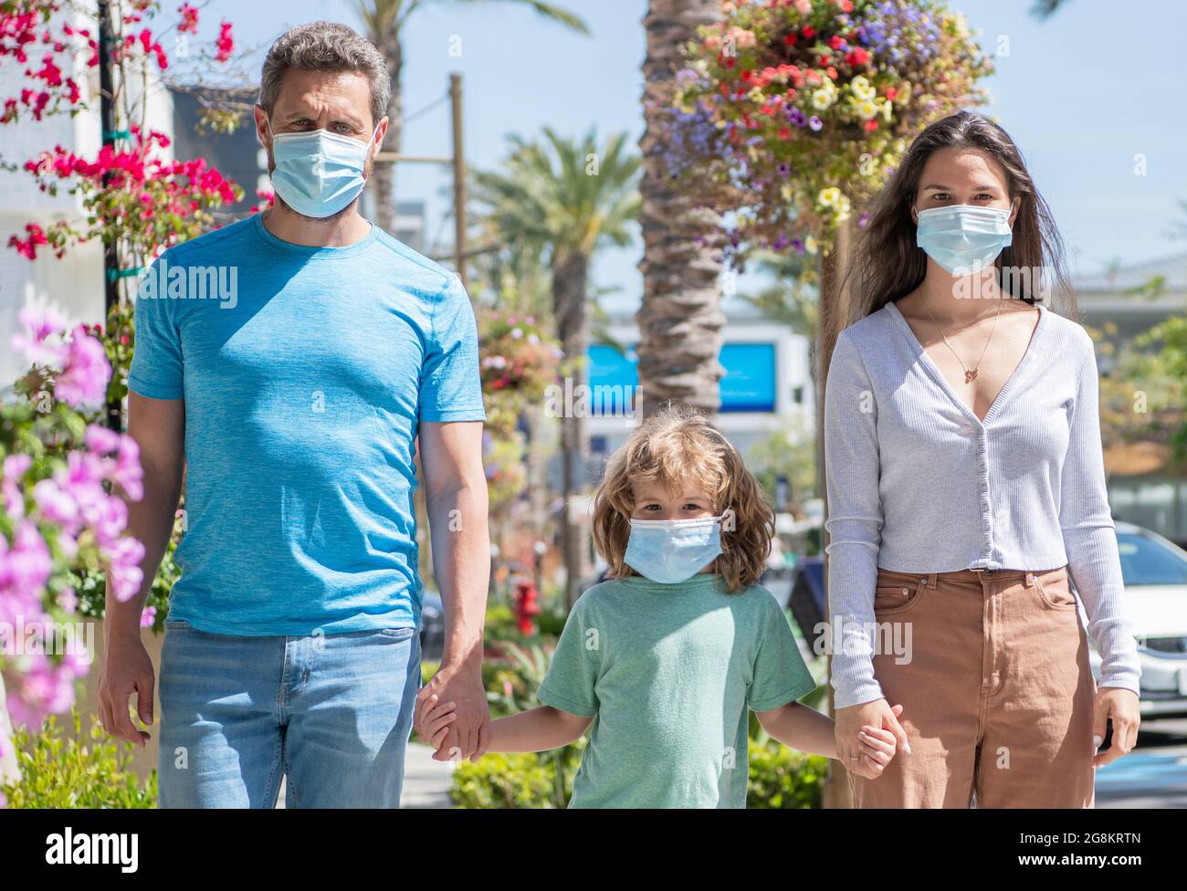 Junge Familie von Mutter Vater und Sohn tragen Schutzmaske zu Fuß im Freien, covid Stockfoto