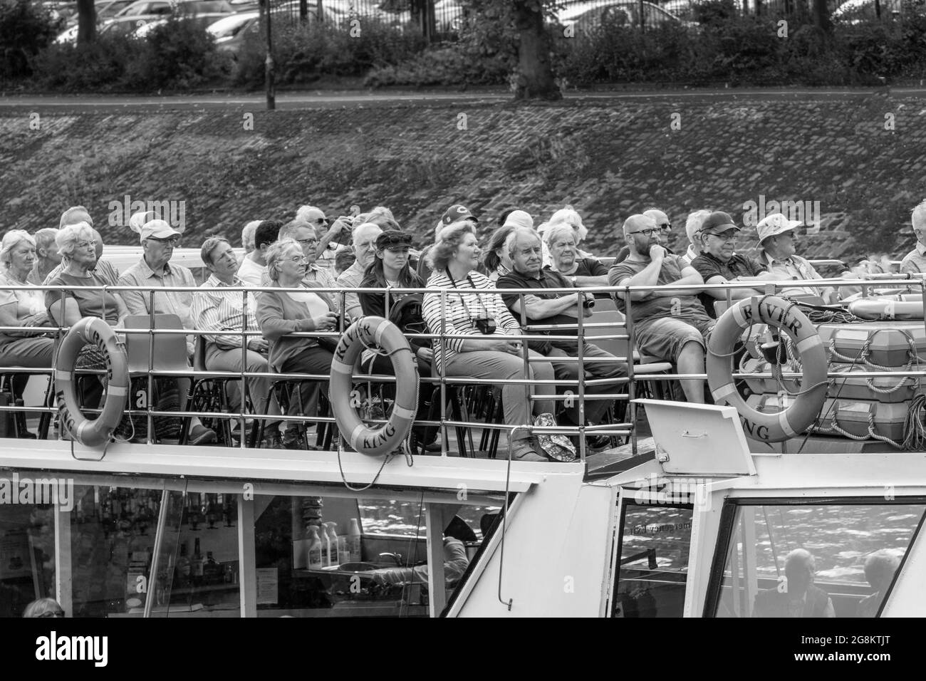 Touristen saßen auf dem Oberdeck eines Kreuzschiffs und nutzten die Gelegenheit für eine Tour entlang des Flusses Ouse, York, North Yorkshire, England, Großbritannien. Stockfoto