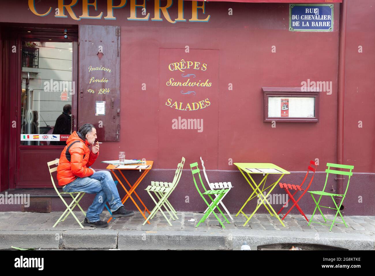 Mann, der auf der Terrasse eines Creperie in Montmartre, Paris raucht Stockfoto