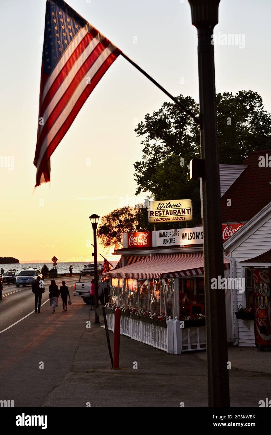 Herrlicher goldener Sonnenuntergang, der im Gelände reflektiert wird, mit Touristen, die zu Wilson's Ice Cream Parlor, gegründet 1906, Ephraim, Door County, Wisconsin, USA Stockfoto
