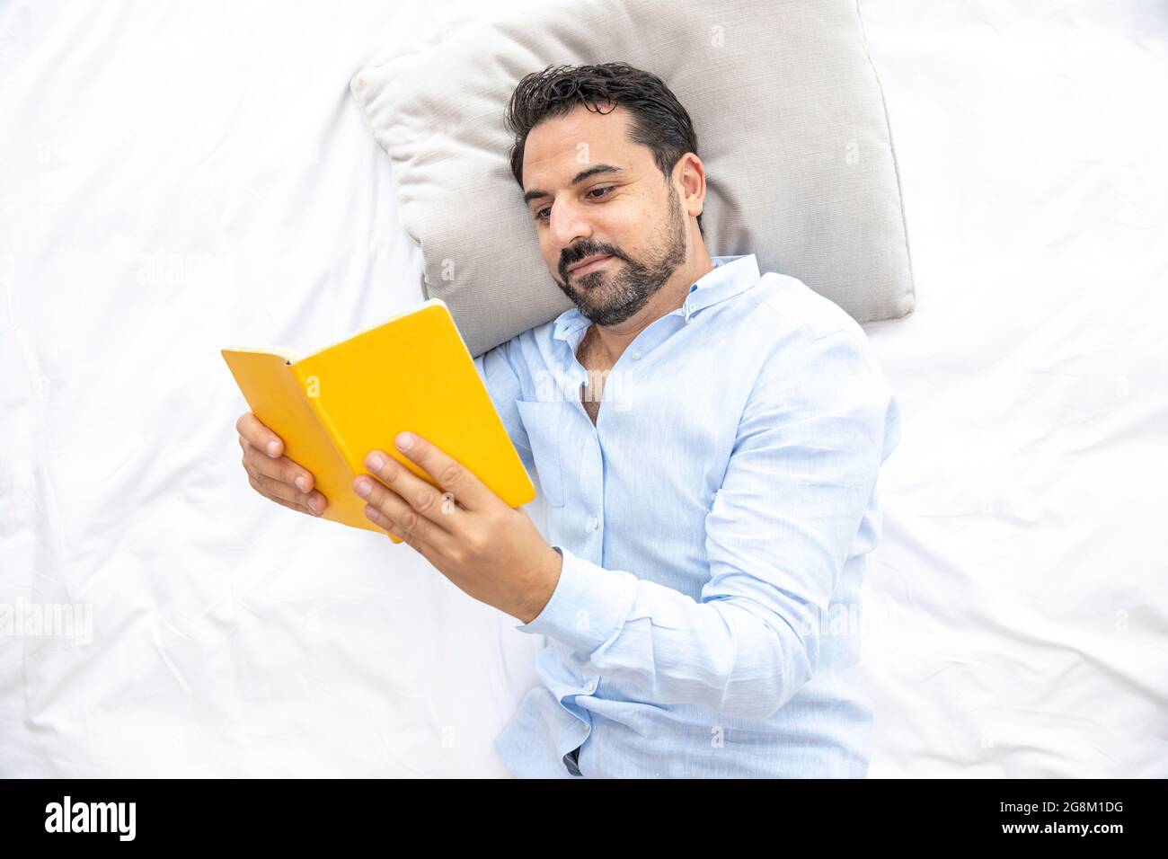 Ein arabischer Mann mittleren Alters liest im Bett Stockfoto