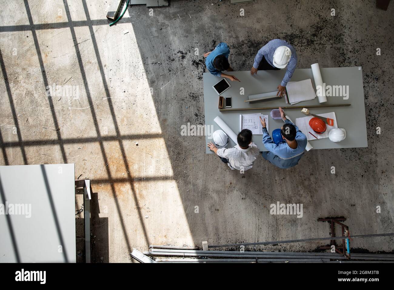 Vier Personen Team von Ingenieuren sprechen zusammen, um Baumaterial zu überprüfen, aufgenommen aus dem hohen Winkel, Draufsicht Foto Stockfoto