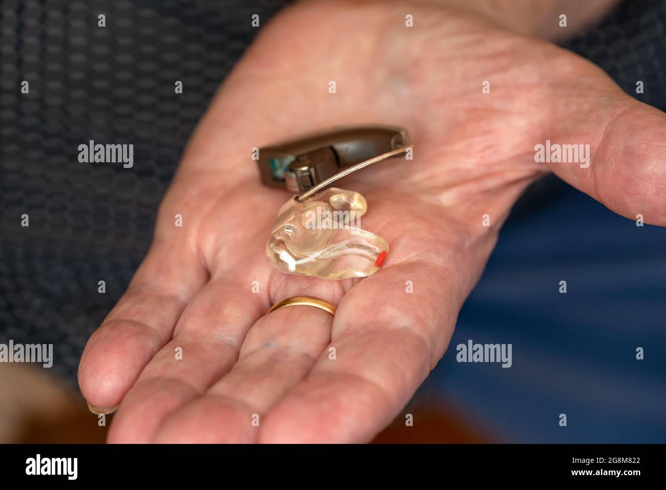 Ältere ältere Frau, die ein Hörgeräteinstrument in der Hand hält, Nahaufnahme Stockfoto