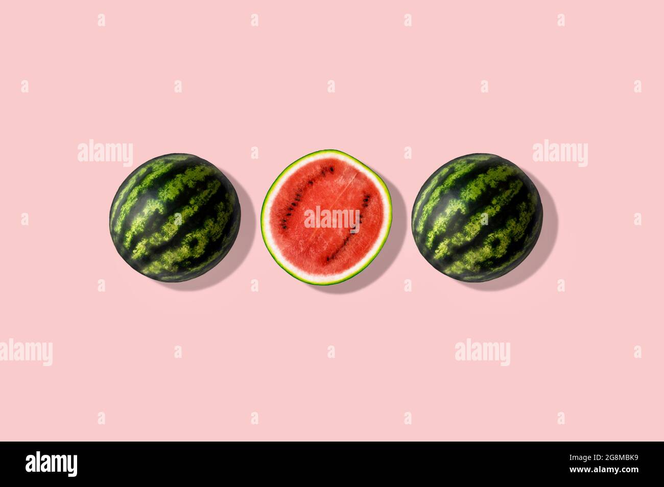 Drei Hälften Wassermelone, isoliert und vor rosa Sommerhintergrund Stockfoto