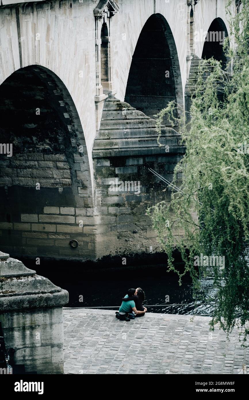 Vertikale Aufnahme eines niedlichen Paares, das unter der Bogenbrücke sitzt Stockfoto