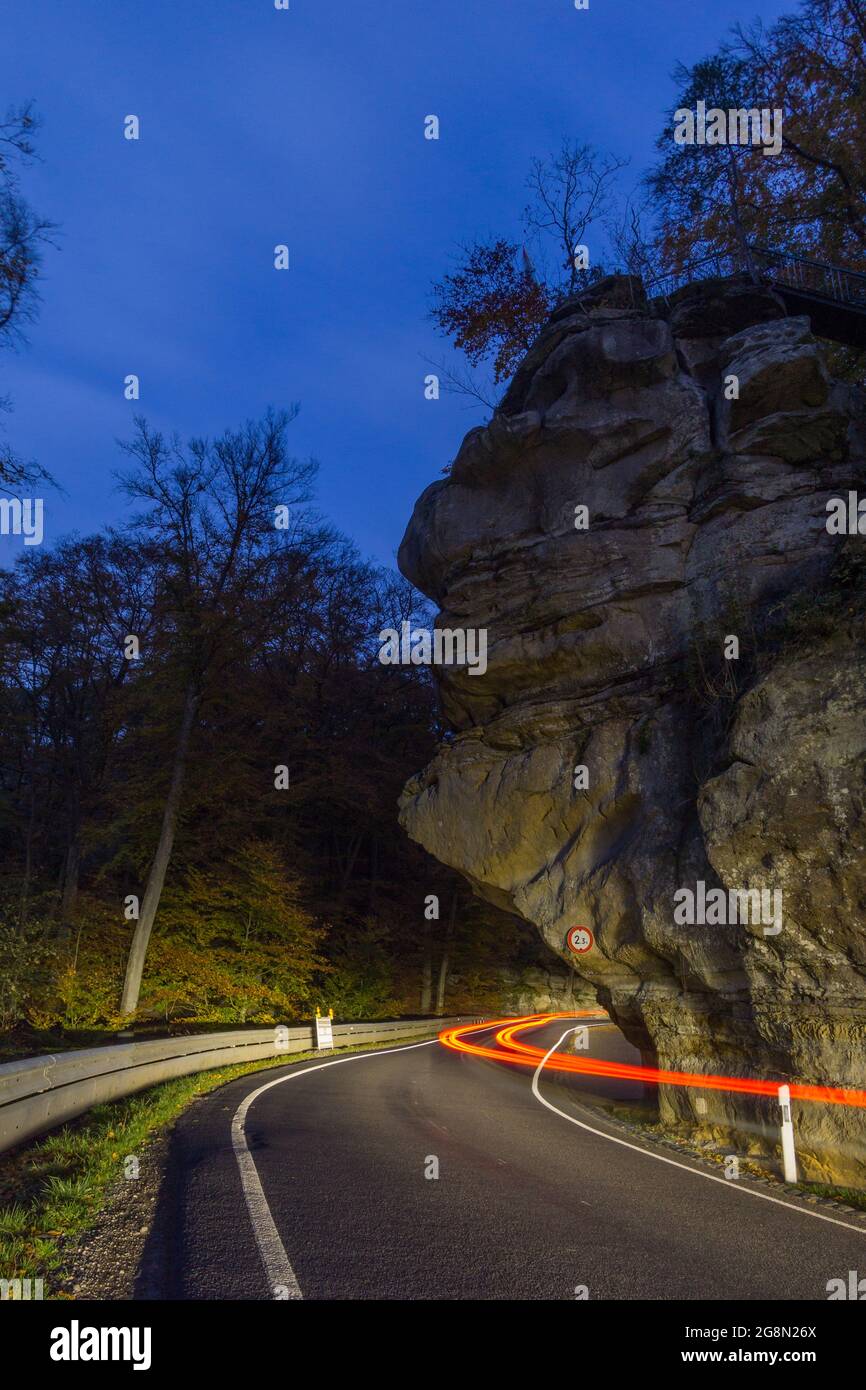 Rote Auto-Light-Trails auf Landstraße mit Felsen in Mullerthal bei Nacht, Luxemburg Stockfoto