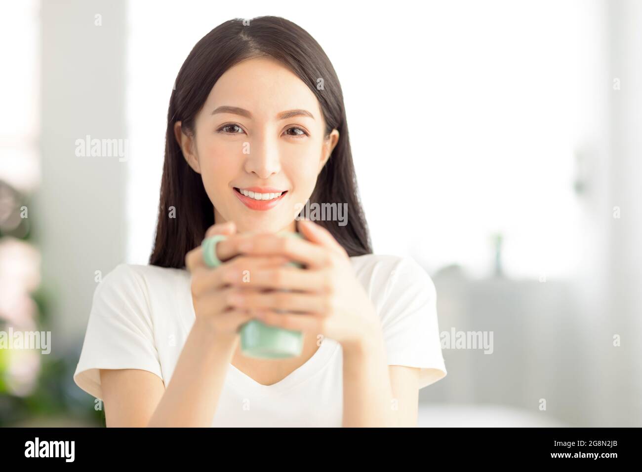 Schöne junge Frau hält eine Tasse Tee im Wohnzimmer zu Hause Stockfoto