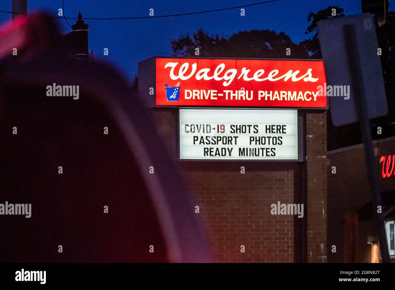 Beleuchtetes Schild für die Walgreens-Apotheke mit COVID-19-Aufnahmen und sofortigen Passfotos in Snellville, Georgia. (USA) Stockfoto