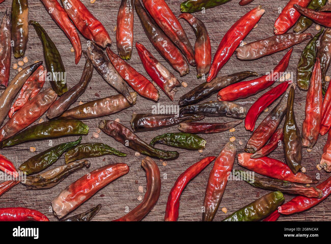 Trockene Chilischoten werden zufällig in der Ebene auf Holzbrettstruktur verstreut Stockfoto