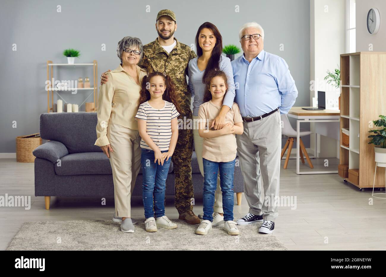 Porträt eines glücklichen Militärveteranen und seiner Familie, die zusammen im Wohnzimmer stehen Stockfoto