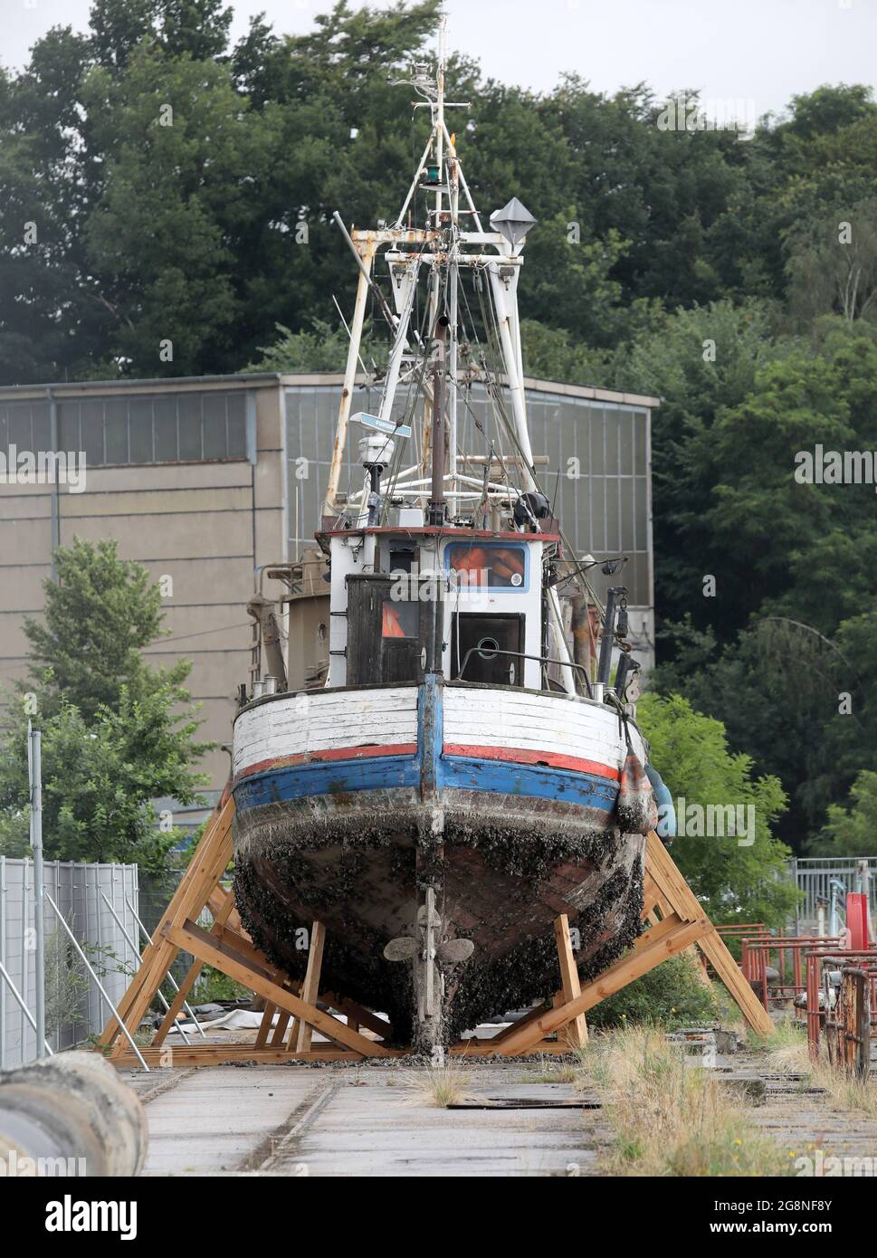 Rostock, Deutschland. Juli 2021. Auf dem Gelände der ehemaligen Neptun-Werft liegen zwei ehemalige Fischkutter an Land. Der ehemalige Fischkutter 'Barth' (l) aus Warnemünde wurde hierher geschleppt und an Land gebracht, weil er kurz vor dem Untergang stand, vor dem ehemaligen Fischkutter 'Wernigerode', der wochenlang auf dem Boden des Stadthafens lag, bevor er gerettet und hierher transportiert wurde. Ob die Fräser verschrottet werden, wird wahrscheinlich noch geklärt, aus wirtschaftlicher Sicht hätten sie wahrscheinlich keine Zukunft mehr. Quelle: Bernd Wüstneck/dpa-Zentralbild/ZB/dpa/Alamy Live News Stockfoto