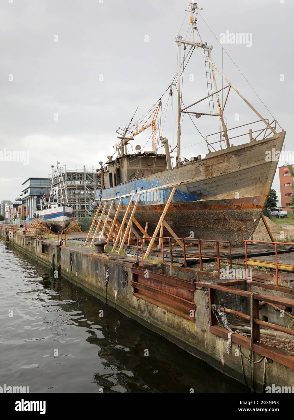 Rostock, Deutschland. Juli 2021. Auf dem Gelände der ehemaligen Neptun-Werft liegen zwei ehemalige Fischkutter an Land. Der ehemalige Fischkutter 'Barth' (l) aus Warnemünde wurde hierher geschleppt und an Land gebracht, weil er kurz vor dem Untergang stand, vor dem ehemaligen Fischkutter 'Wernigerode', der wochenlang auf dem Boden des Stadthafens lag, bevor er gerettet und hierher transportiert wurde. Ob die Fräser verschrottet werden, wird wahrscheinlich noch geklärt, aus wirtschaftlicher Sicht hätten sie wahrscheinlich keine Zukunft mehr. Quelle: Bernd Wüstneck/dpa-Zentralbild/ZB/dpa/Alamy Live News Stockfoto