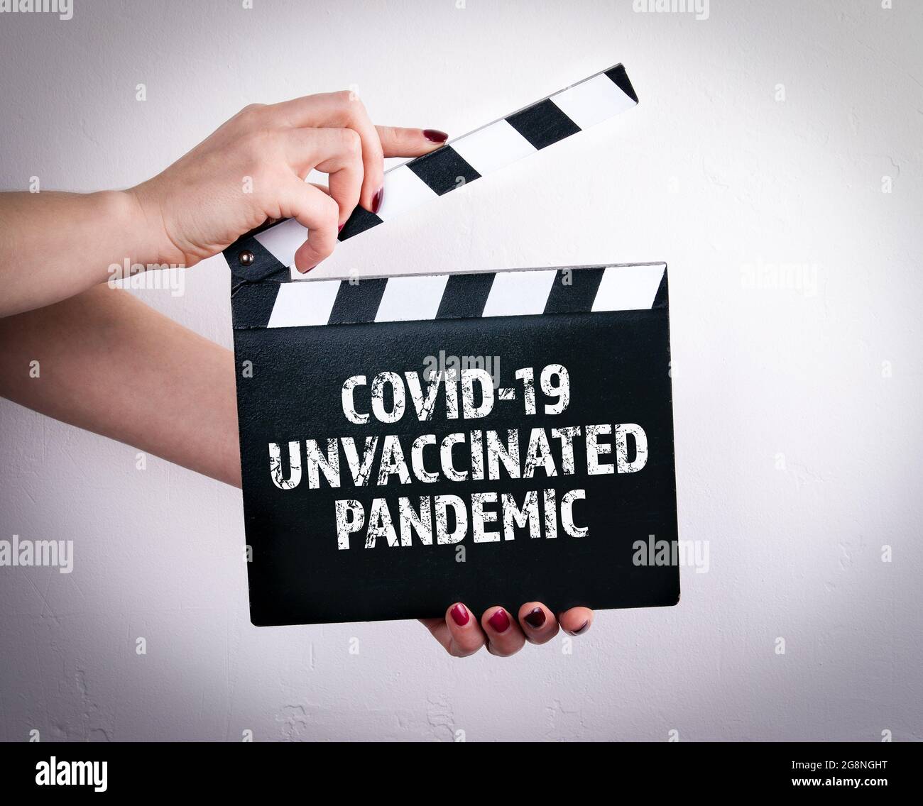 Covid-19 ungeimpfte Pandemie. Weibliche Hände mit Filmklapper. Stockfoto