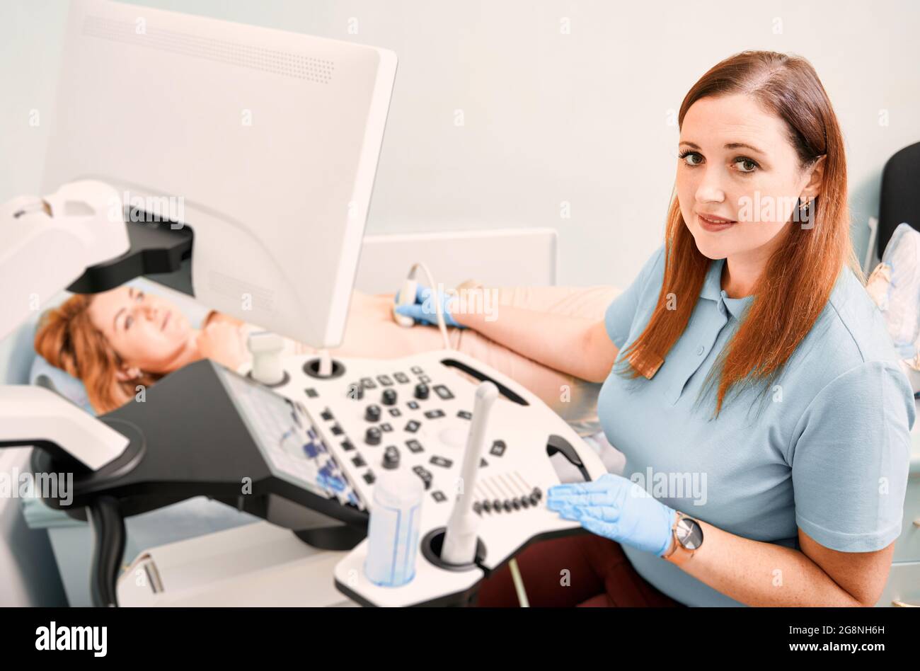 Sonografin mit sterilen Handschuhen, die weibliche Patientin mit einem Ultraschallgerät untersucht. Ärztin bei Ultraschalluntersuchung. Konzept des Gesundheitswesens, ultr Stockfoto
