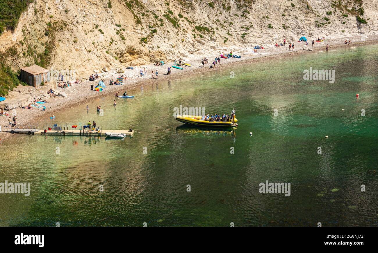 Touristen, die an einem sonnigen Tag mit klarem Wasser auf eine Bootsfahrt an der Jurassic Coast nach Durdle Door mit der Lulworth Rib Ride Company fahren. Stockfoto