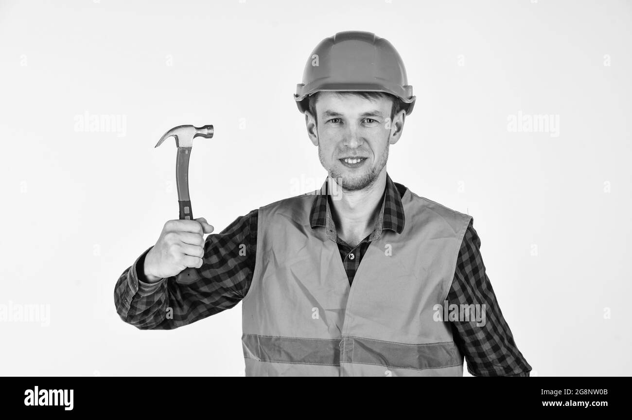 Junger Arbeiter ist Ingenieur-Assistent. Reparateur in Uniform. Mann arbeiten mit Hammer. Echte Bauarbeiter in Helm. Schreiner bereit zu arbeiten. Gebäude Stockfoto