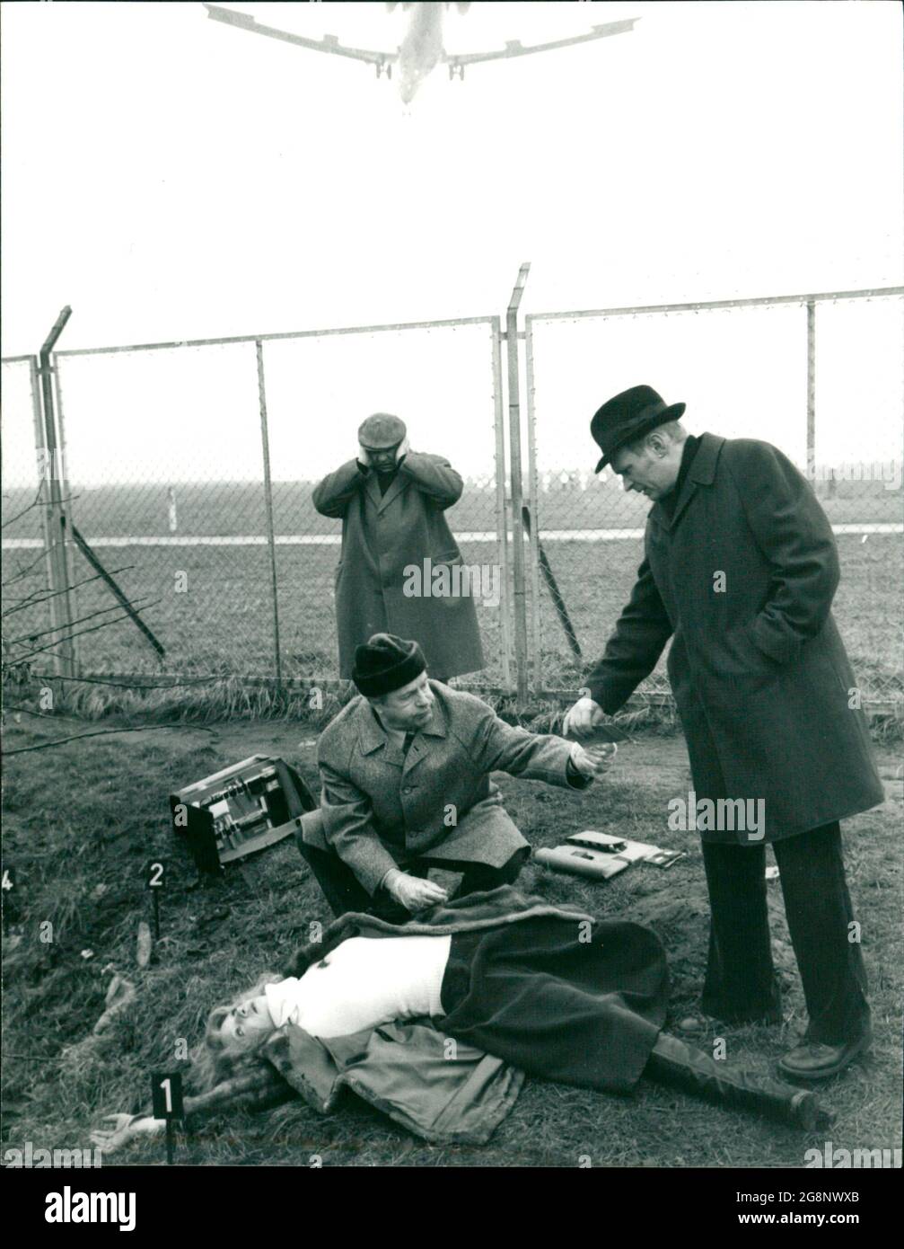 Schon wieder hat der Mörder zugeschlagen. Eine junge Prostituierte ist neben dem Flughafengelände gefunden worden. Kommissar Trimmel und sein Assistent Petersen nehmen die Erhebungen auf. (Vorne: Kleindarsteller, hinten: l. Walter Richter, r. Ulrich von Bock) Stockfoto